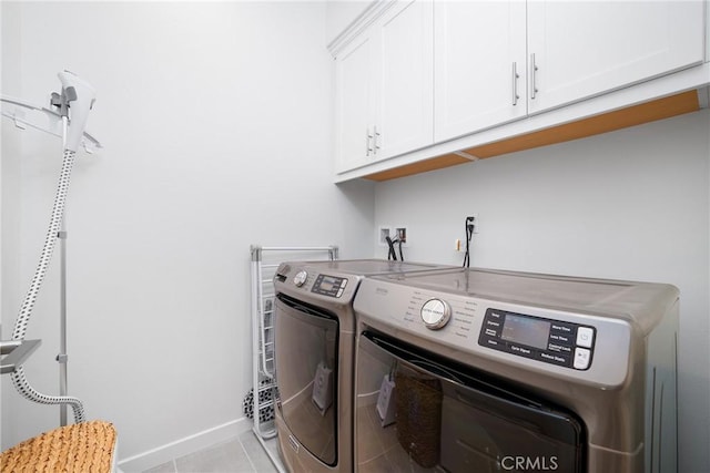 laundry room featuring light tile patterned floors, cabinet space, baseboards, and separate washer and dryer