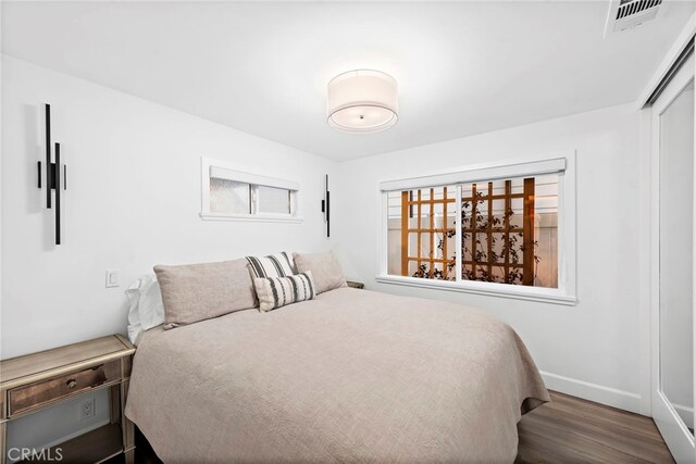 bedroom with wood finished floors, visible vents, and baseboards