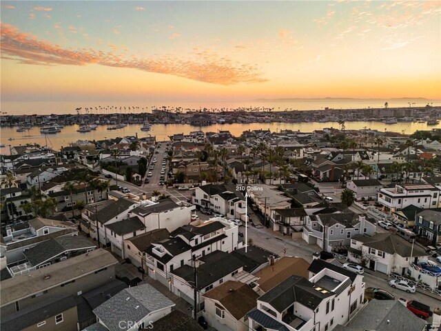 aerial view at dusk featuring a residential view and a water view