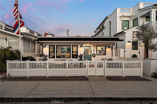 townhome / multi-family property with covered porch, a fenced front yard, and a gate