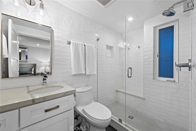 bathroom with tile walls, visible vents, toilet, a stall shower, and vanity