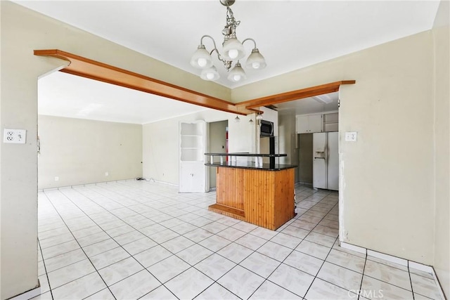 kitchen featuring a notable chandelier, open floor plan, stainless steel microwave, dark countertops, and fridge with ice dispenser