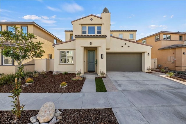 mediterranean / spanish-style home with an attached garage, fence, a tile roof, driveway, and stucco siding