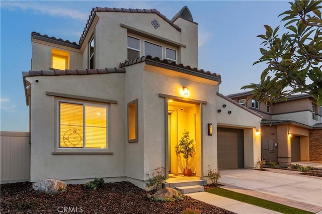 mediterranean / spanish-style home featuring driveway, a tile roof, a garage, and stucco siding