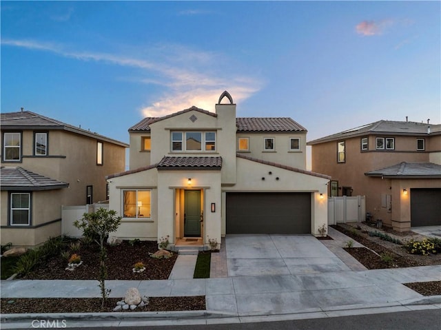 view of front of house with concrete driveway, a tile roof, fence, and stucco siding