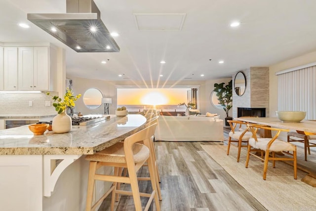 kitchen featuring light stone counters, light wood-style flooring, open floor plan, white cabinetry, and extractor fan