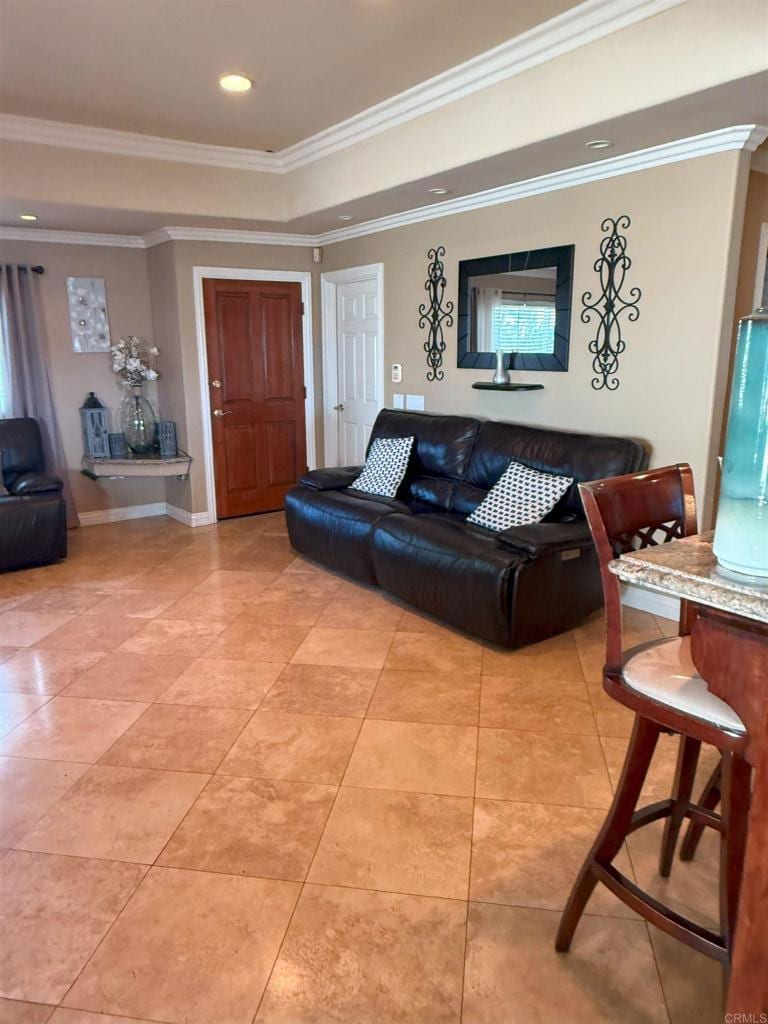 living area featuring a tray ceiling, recessed lighting, ornamental molding, light tile patterned flooring, and baseboards