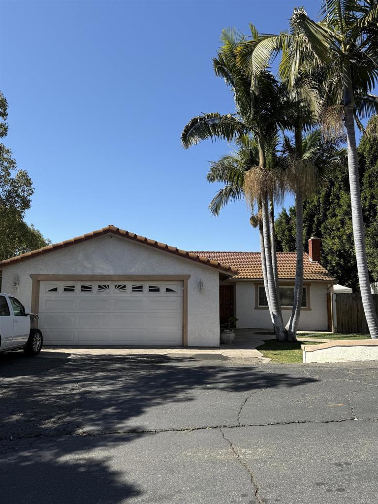 view of front of home with a tile roof, a chimney, stucco siding, an attached garage, and driveway