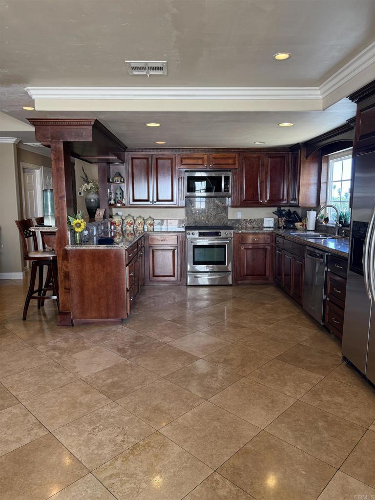 kitchen with visible vents, dark countertops, appliances with stainless steel finishes, crown molding, and a sink