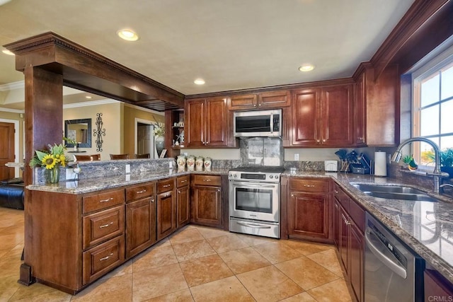 kitchen featuring ornamental molding, a sink, a peninsula, appliances with stainless steel finishes, and stone counters