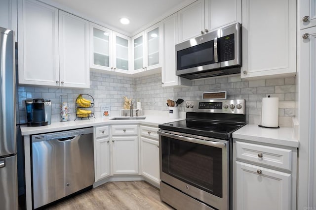 kitchen with light countertops, appliances with stainless steel finishes, glass insert cabinets, and white cabinets