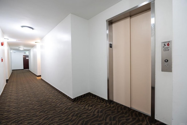 hall with elevator and dark carpet