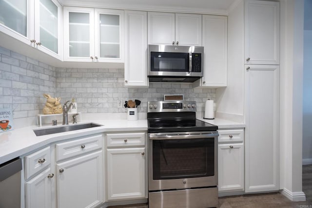 kitchen featuring stainless steel appliances, light countertops, and glass insert cabinets