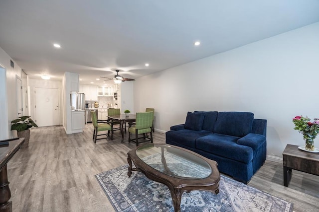 living room featuring ceiling fan, recessed lighting, light wood-style flooring, and baseboards