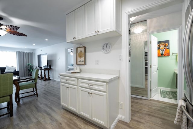 kitchen featuring ceiling fan, white cabinets, light countertops, wood finished floors, and baseboards