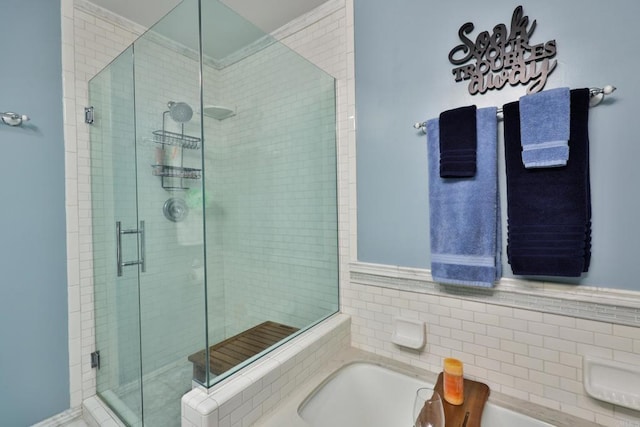 full bathroom with a stall shower, a bath, and tile walls
