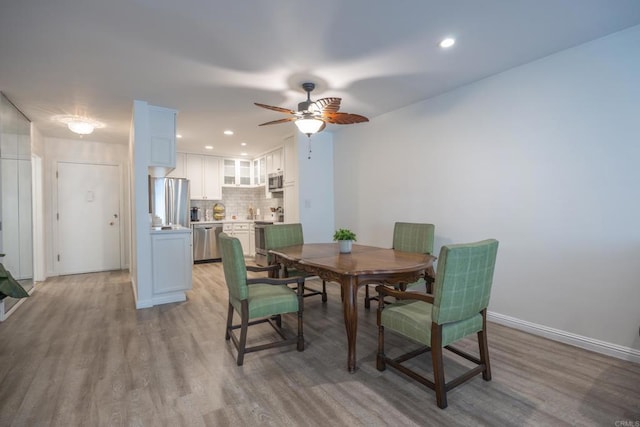 dining space featuring light wood-style flooring, a ceiling fan, baseboards, and recessed lighting