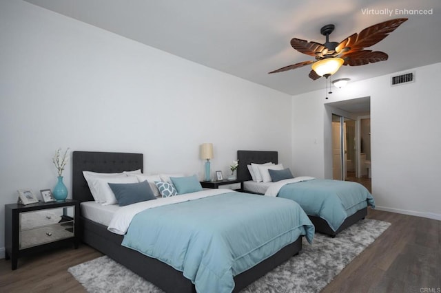 bedroom with wood finished floors, baseboards, a ceiling fan, and ensuite bath