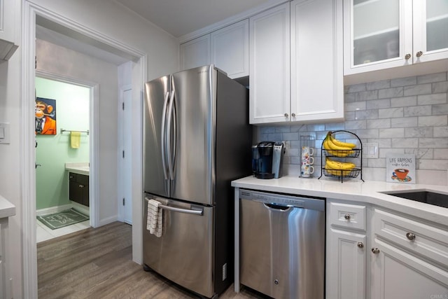kitchen featuring stainless steel appliances, white cabinetry, light countertops, and wood finished floors