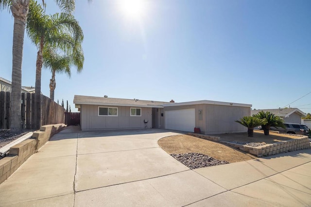 single story home featuring concrete driveway, fence, and an attached garage