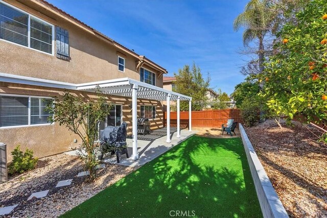 rear view of property with a patio, stucco siding, a fenced backyard, and a pergola