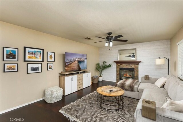 living area featuring dark wood-style floors, a fireplace, visible vents, and baseboards