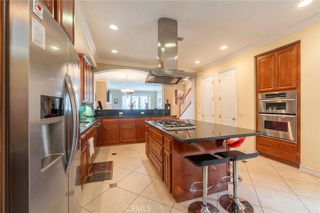 kitchen with island range hood, a kitchen island, appliances with stainless steel finishes, a breakfast bar area, and a peninsula
