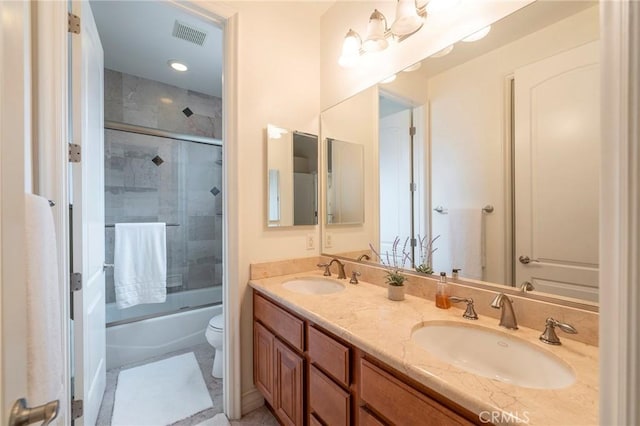 bathroom with enclosed tub / shower combo, a sink, toilet, and double vanity