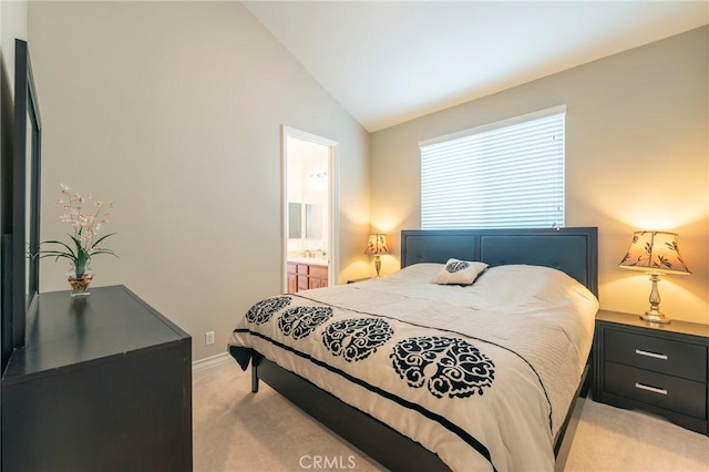 bedroom with lofted ceiling, light colored carpet, ensuite bath, and baseboards