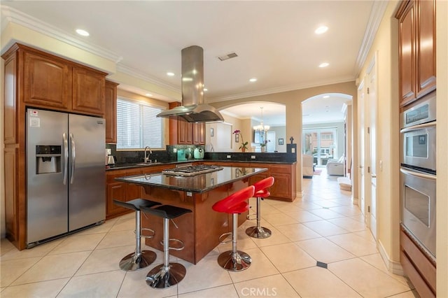 kitchen featuring arched walkways, a kitchen island, appliances with stainless steel finishes, a breakfast bar area, and island exhaust hood