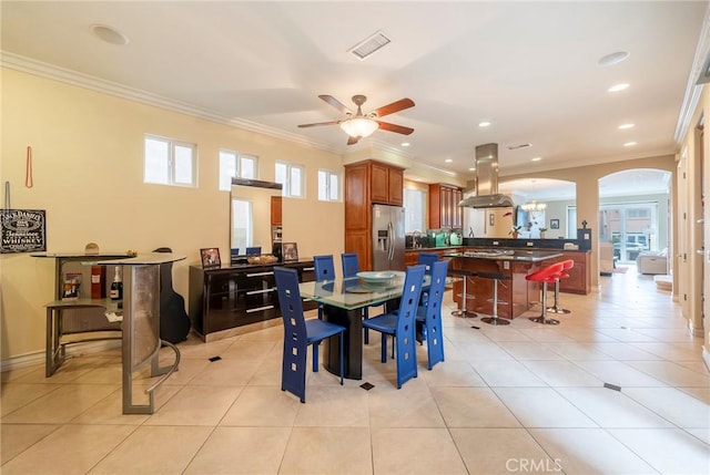 dining space with light tile patterned floors, visible vents, arched walkways, and crown molding