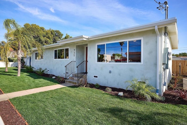 ranch-style house with a front yard, fence, and stucco siding