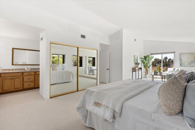 bedroom featuring a closet, visible vents, light carpet, connected bathroom, and a sink