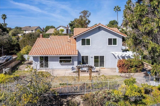 rear view of property featuring a tile roof, a patio, stucco siding, a pergola, and a fenced backyard