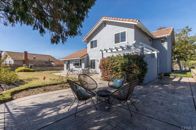 rear view of property featuring a patio area, fence, a tile roof, and a pergola