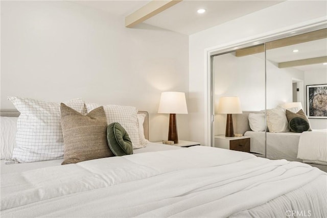 bedroom with beamed ceiling, a closet, and recessed lighting