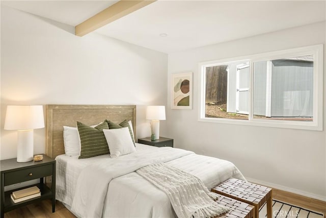 bedroom featuring beamed ceiling, baseboards, and wood finished floors