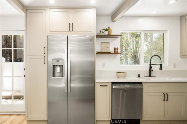 kitchen with appliances with stainless steel finishes, cream cabinets, and a sink