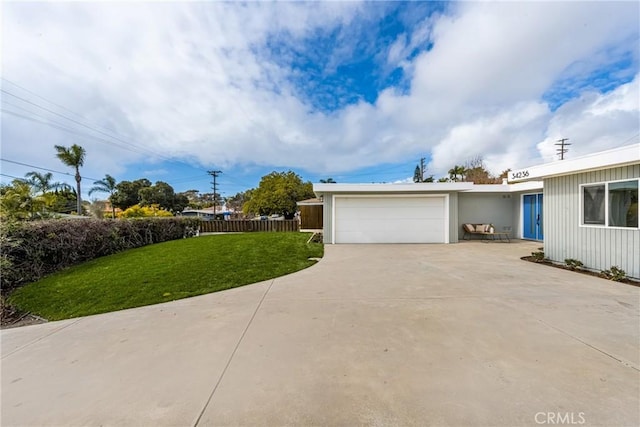 view of front of property featuring concrete driveway, a front lawn, an attached garage, and fence