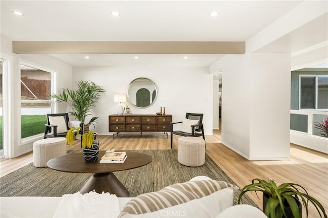 living area featuring baseboards, recessed lighting, beam ceiling, and light wood-style floors