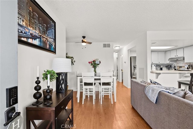 dining space with visible vents, ceiling fan, a textured ceiling, and light wood finished floors