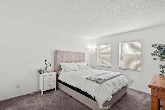 bedroom featuring baseboards, dark carpet, and a textured ceiling