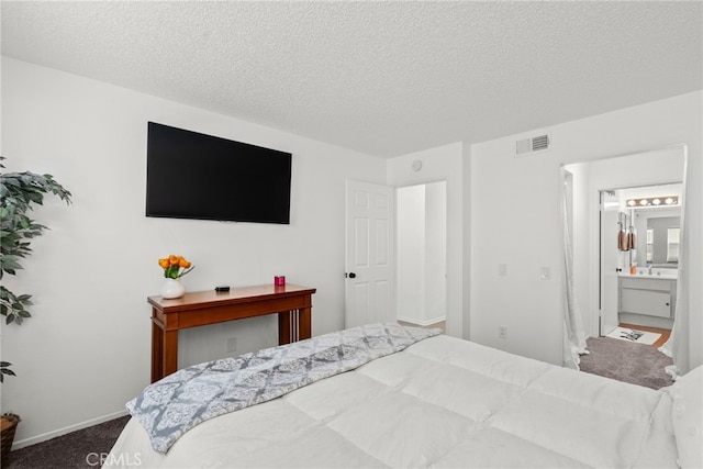 carpeted bedroom with baseboards, visible vents, a textured ceiling, and ensuite bathroom