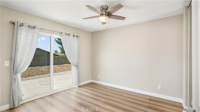 empty room featuring light wood finished floors, a ceiling fan, and baseboards