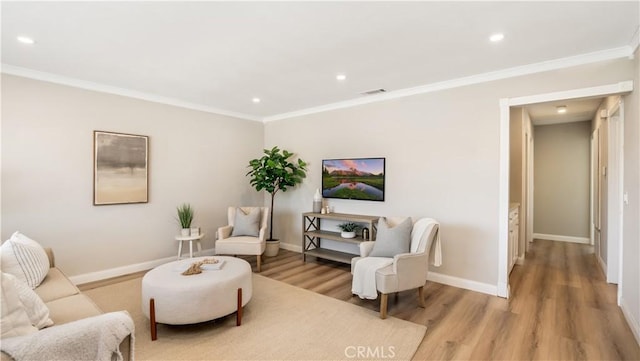 living area with baseboards, visible vents, wood finished floors, and ornamental molding