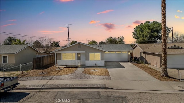 view of front of property featuring driveway, an attached garage, fence, and stucco siding