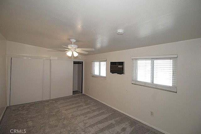 unfurnished bedroom with carpet, a closet, a wall mounted air conditioner, and ceiling fan