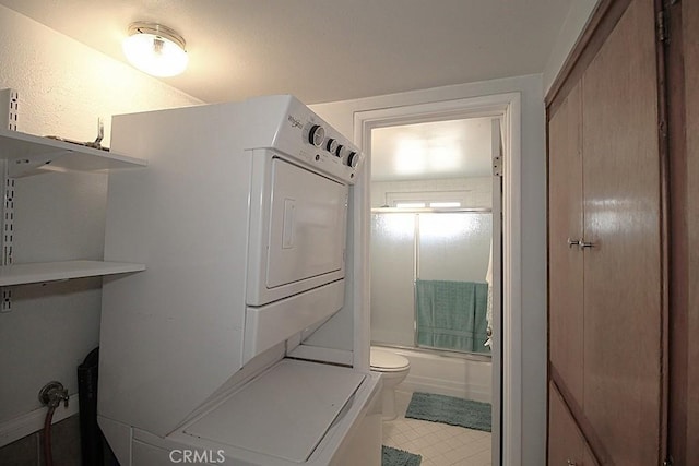 bathroom with stacked washer and dryer and bath / shower combo with glass door