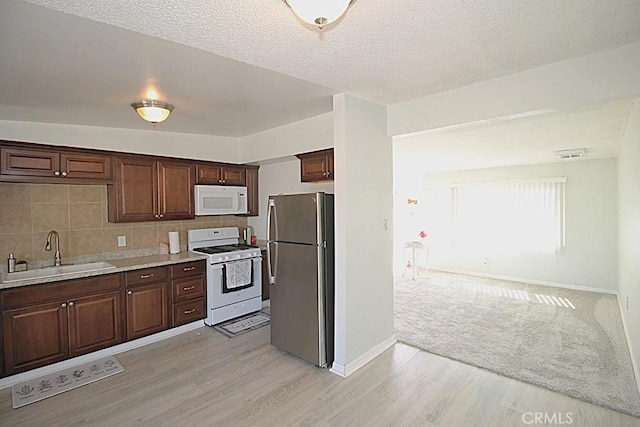 kitchen featuring light countertops, white appliances, a sink, and dark brown cabinets