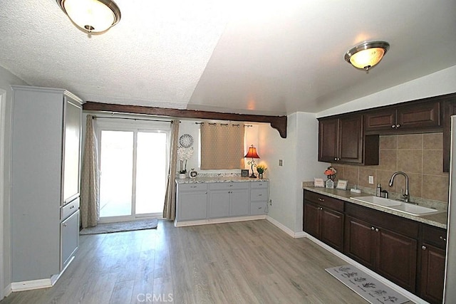 kitchen featuring light wood-type flooring, dark brown cabinetry, light countertops, and a sink